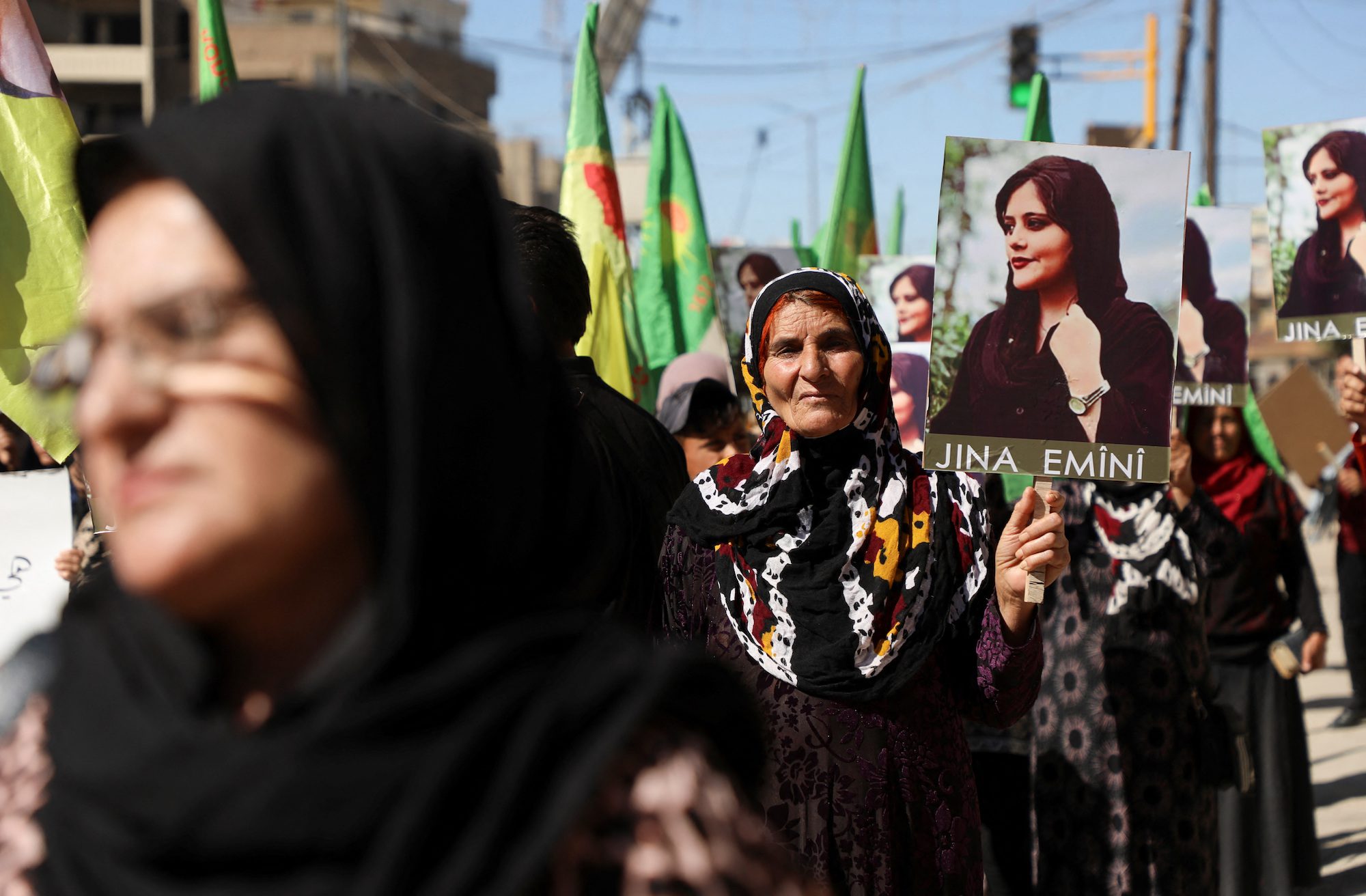 Women carry flags and pictures during a protest over the death of 22-year-old Kurdish woman Mahsa Amini in Iran, in the Kurdish-controlled city of Qamishli, northeastern Syria September 26, 2022.  REUTERS/Orhan Qereman 