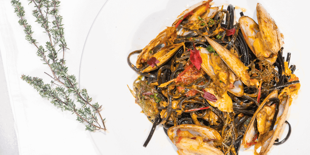 Surf Clams with Red Kimchi, Nduja Butter Sauce, Squid Ink Linguini & Sea Vegetables