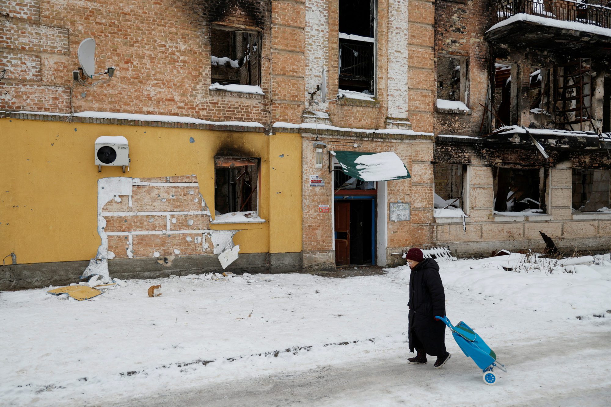 FILE PHOTO: A local woman walks next to a wall of a residential building, heavily damaged during Russian invasion, from which a group of people tried to steal the work of street artist Banksy, in the town of Hostomel, Kyiv region, Ukraine December 3, 2022.  REUTERS/Valentyn Ogirenko