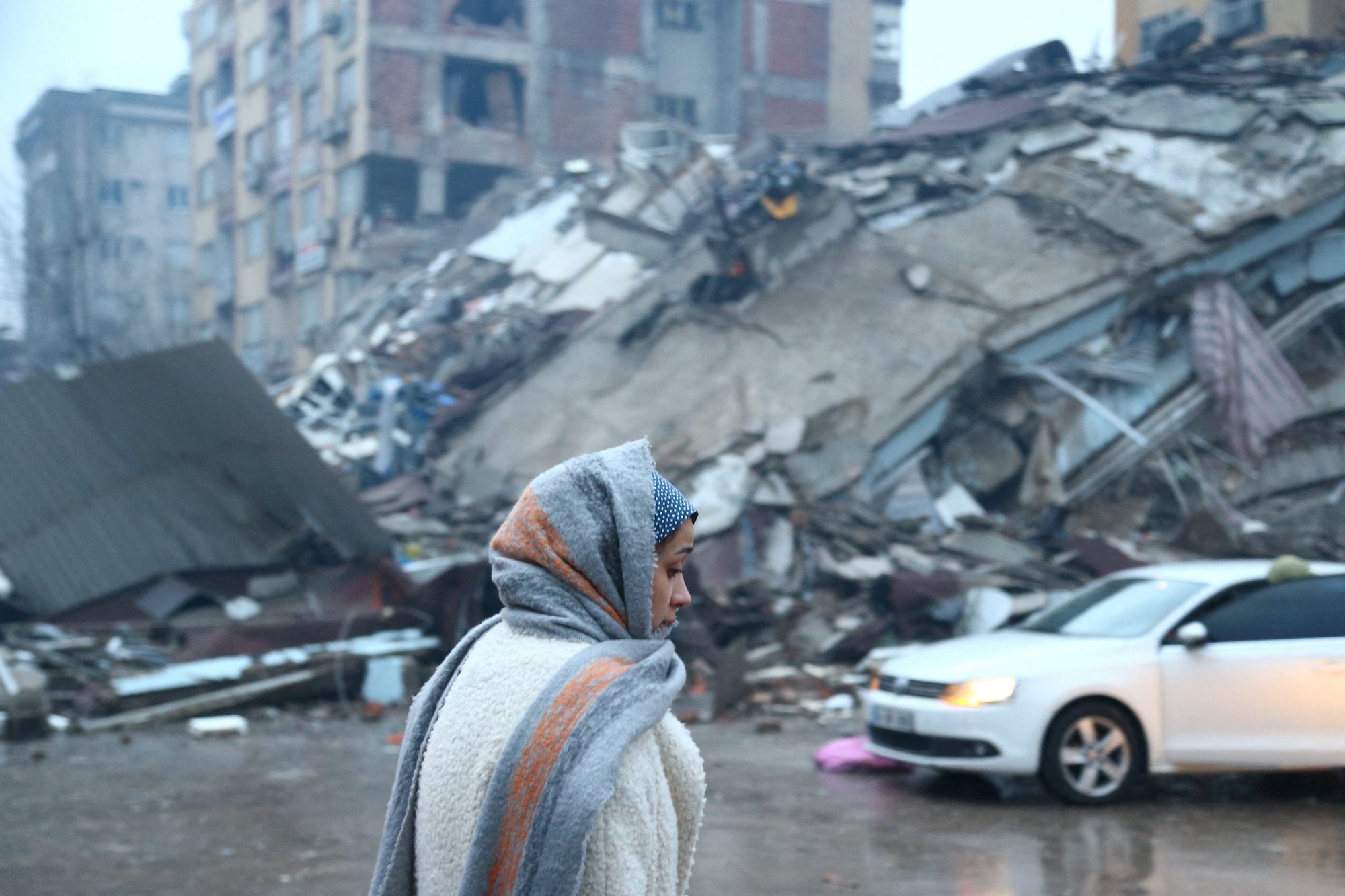 A woman stands near a collapsed building after an earthquake in Kahramanmaras, Turkey February 6, 2023. REUTERS/Cagla Gurdogan