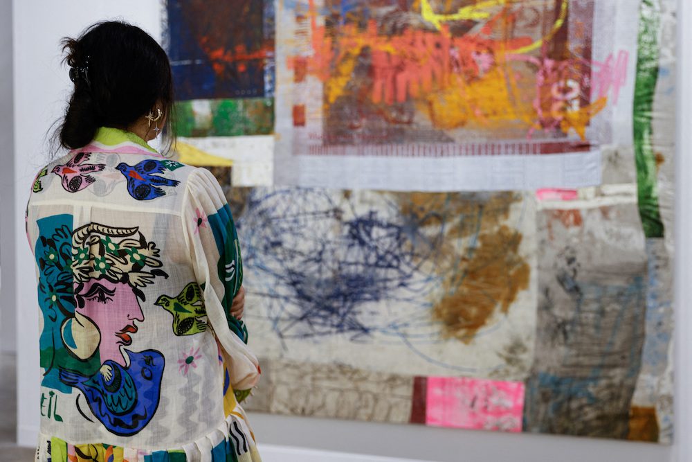 A woman looks at an artwork titled "Communal Play" by Oscar Murillo at Art Basel in Hong Kong, China, March 23, 2023. REUTERS/Tyrone Siu