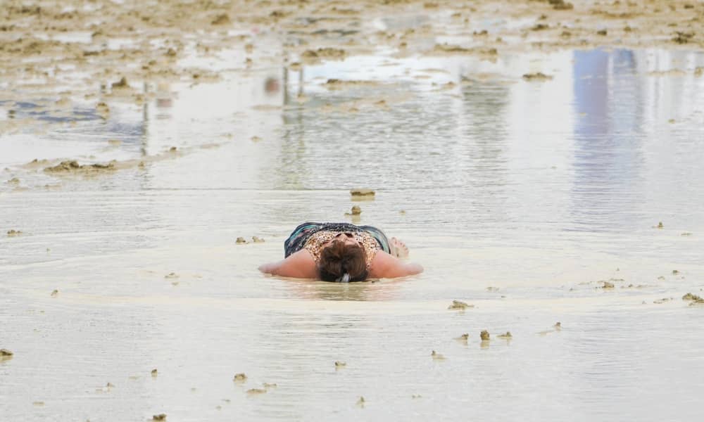 A Burning Man attendee lies down in the mud and water at the event in Black Rock City, in the Nevada desert, after a rainstorm turned the site into mud September 2, 2023. Trevor Hughes/USA TODAY NETWORK via REUTERS