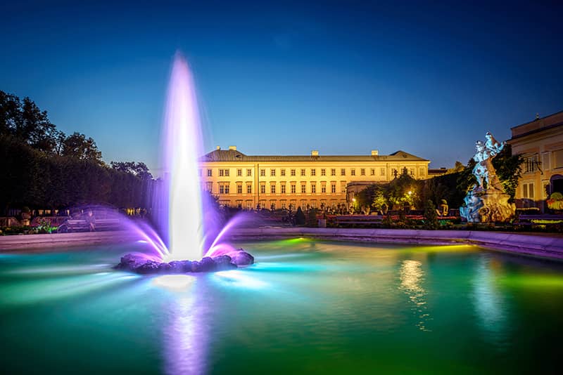 At night, the Salzburg-Fountain in the Mirabell Gardens offers a captivating view of the Mirabell Palace, as captured in this stunning photograph by Günter Breitegger on behalf of Tourismus Salzburg.