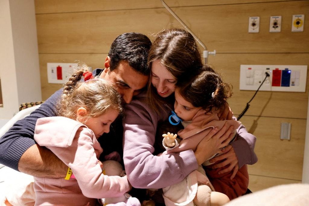Aviv Asher, 2,5-year-old, her sister Raz Asher, 4,5-year-old, and mother Doron, react as they meet with Yoni, Raz and Aviv's father and Doron's husband, after they returned to Israel to the designated complex at the Schneider Children's Medical Center, during a temporary truce between Hamas and Israel, in Petah Tikva, Israel, in this handout picture released on November 25, 2023. Schneider Children's Medical Center Spokesperson/Handout via REUTERS.