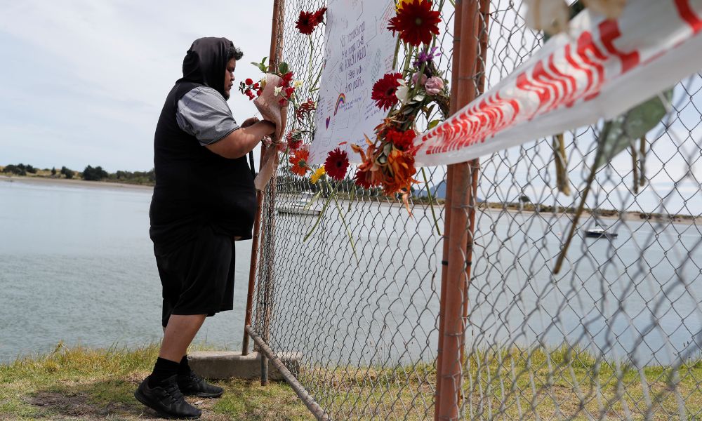 FILE PHOTO: A man offers flowers at a memorial at the harbour in Whakatane, following the White Island volcano eruption in New Zealand, December 11, 2019. REUTERS/Jorge Silva/File Photo