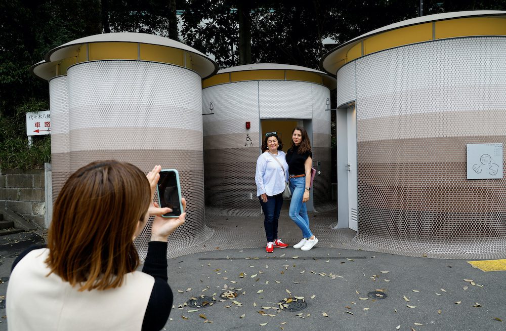 Foreign tourists get their photos taken in front of a public toilet which was redesigned as part of a project to transform public toilets into restrooms that can be used comfortably by everyone, during a Tokyo Toilet Shuttle Tour, at Shibuya ward, in Tokyo, Japan April 4, 2024. REUTERS/Kim Kyung-Hoon