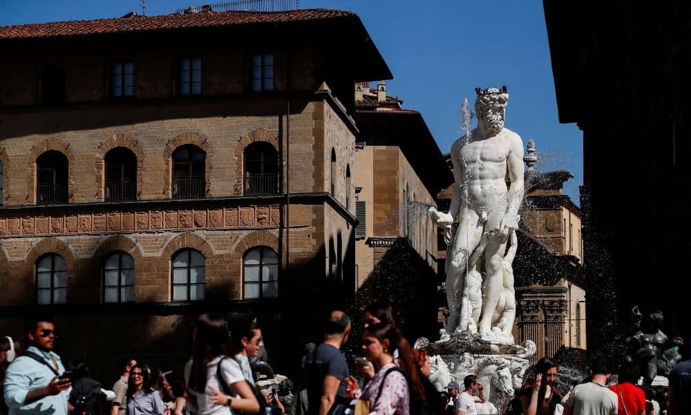 People walk past the Fountain of Neptune (Fontana del Nettuno) in Signoria Square in Florence, Italy