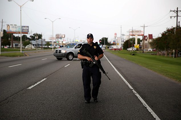 A police officer blocks off a road near the scene of a fatal shooting of police officers in Baton Rouge, Louisiana, United States. REUTERS/Joe Penney.