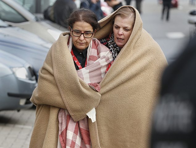 People wrapped in blankets leave the scene of explosions at Zaventem airport near Brussels. REUTERS/Francois Lenoir 