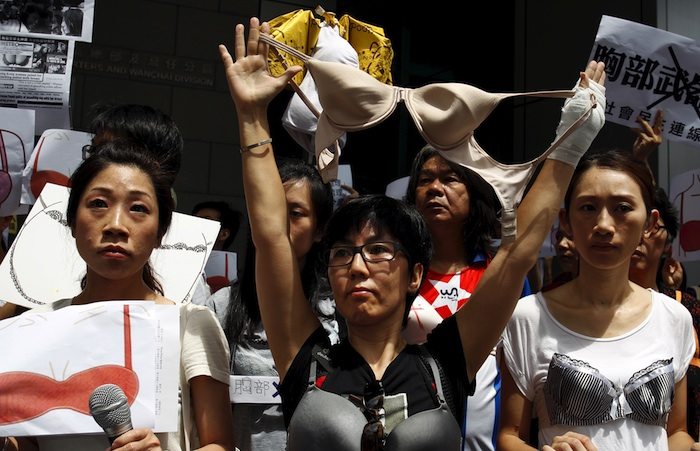 Protesters wear bras over their shirts during a demonstration in support of local female protester Ng Lai-ying, outside the police headquarters in Hong Kong, China August 2, 2015. Ng was sentenced to three and a half months in jail for using her breast to bump against police at an anti-parallel trading protest, local media reported.   REUTERS/Liau Chung-ren - RTX1MPM4