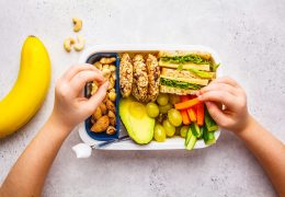 School healthy lunch box with sandwich, cookies, fruits and avocado on white background.