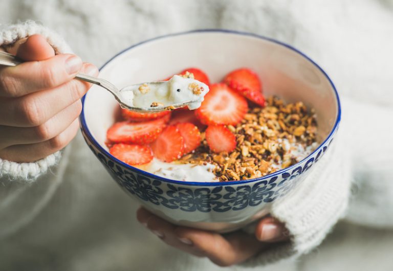 Healthy breakfast yogurt, granola, strawberry bowl in woman's hands