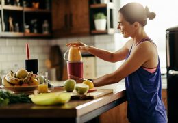 Young sportswoman making healthy smoothie in the kitchen.