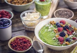 Green breakfast smoothie in bowl with superfoods like chia, quinoa, goji, fresh berries and sunflower seeds is a great way to increase your vitamin intake.