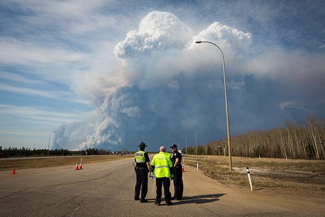 Officers look on as smoke from Fort McMurray's raging wildfires billow into the air after the city was evacuated.
REUTERS/Topher Seguin 