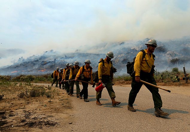 U.S. Forest Service firefighters walk to their truck after battling a wildfire near Potrero California. REUTERS/Mike Blake      