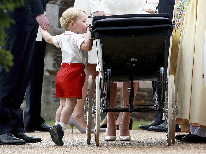 Britain's Prince George looks into the pram of his sister Princess Charlotte after her christening at the Church of St. Mary Magdalene in Sandringham, Britain July 5, 2015. 