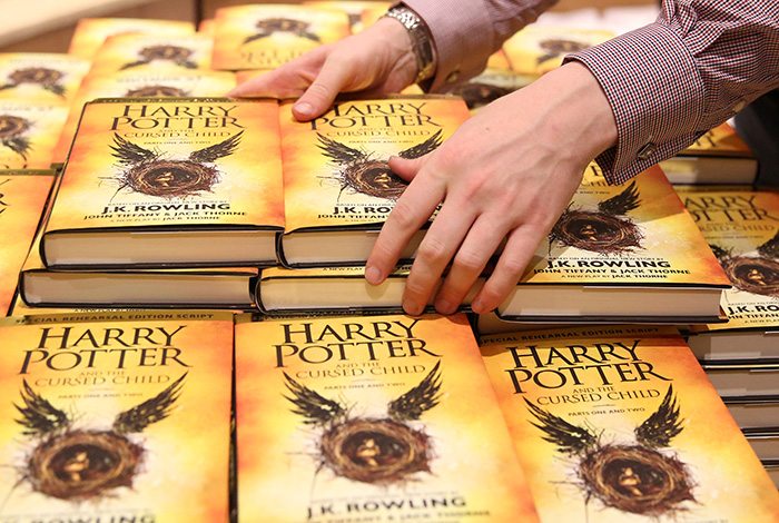 A store assistant holds copies of the book of the play of Harry Potter and the Cursed Child parts One and Two at a bookstore in London, Britain July 31, 2016. REUTERS/Neil Hall