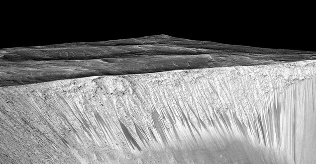 Dark narrow streaks called recurring slope lineae emanating out of the walls of Garni crater on Mars are seen in an image produced by NASA, Jet Propulsion Laboratory (JPL) and the University of Arizona. 