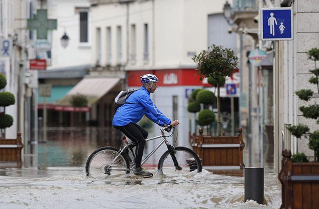 A man cycles in a flooded street near the clinic of Montargis in the Loiret, following heavy rain in Franc. REUTERS/Christian Hartmann