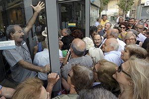 Pensioners struggle to enter a National Bank branch to receive part of their pension in Iraklio on the island of Crete, Greece, July 2, 2015. Long lines of pensioners jostling to get into a limited number of banks opened specially to pay out retirement benefits have become a powerful symbol of the misery facing Greece and the problems mounting for Prime Minister Alexis Tsipras. REUTERS/Stefanos Rapanis TPX IMAGES OF THE DAY      - RTX1IPRT