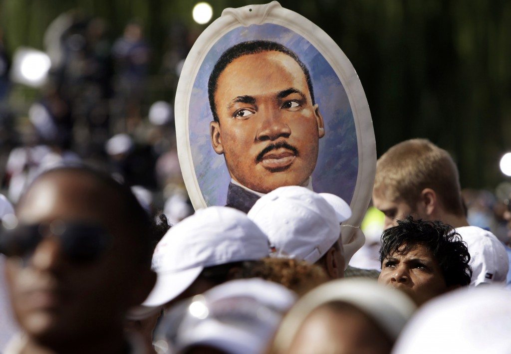 A woman holds a portrait of Martin Luther King, Jr. at a memorial dedication. REUTERS/Yuri Gripas