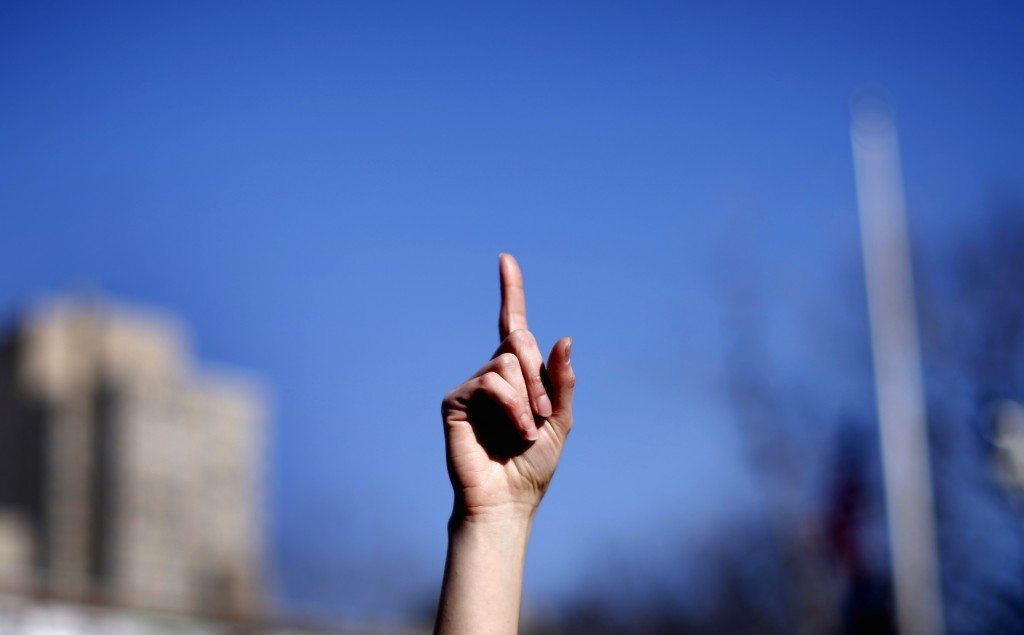 A woman raises a finger to the air as she dances with others to the theme song of the "One Billion Rising" campaign in New York City's Washington Square Park on Valentines Day. REUTERS/Mike Segar