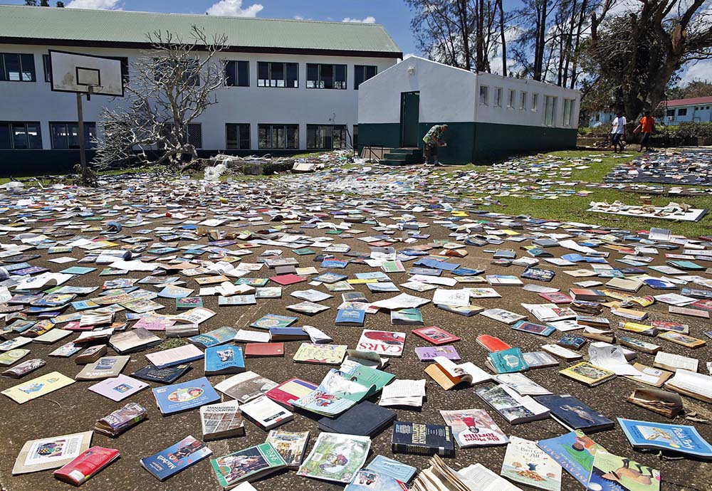 Headmaster Hatyay and teachers of Central School lay out books to dry in the sun after the roof of the school's library was blown away by Cyclone Pam in Port Vila