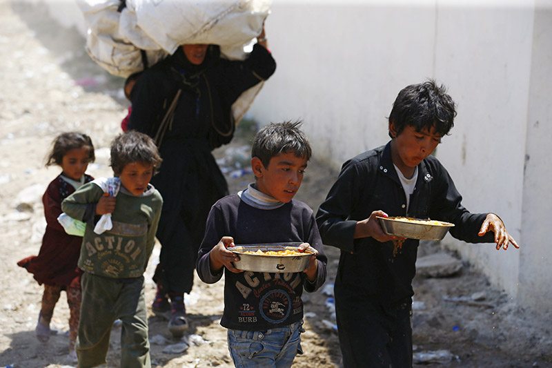 Syrian refugee boys carry food as they cross into Turkey at the Akcakale border gate in Sanliurfa province, Turkey, June 16, 2015. More than 23,000 refugees fleeing fighting in northern Syria have crossed into Turkey, the United Nations refugee agency said on Tuesday, quoting Turkish authorities.   REUTERS/Umit Bektas - RTX1GPYP