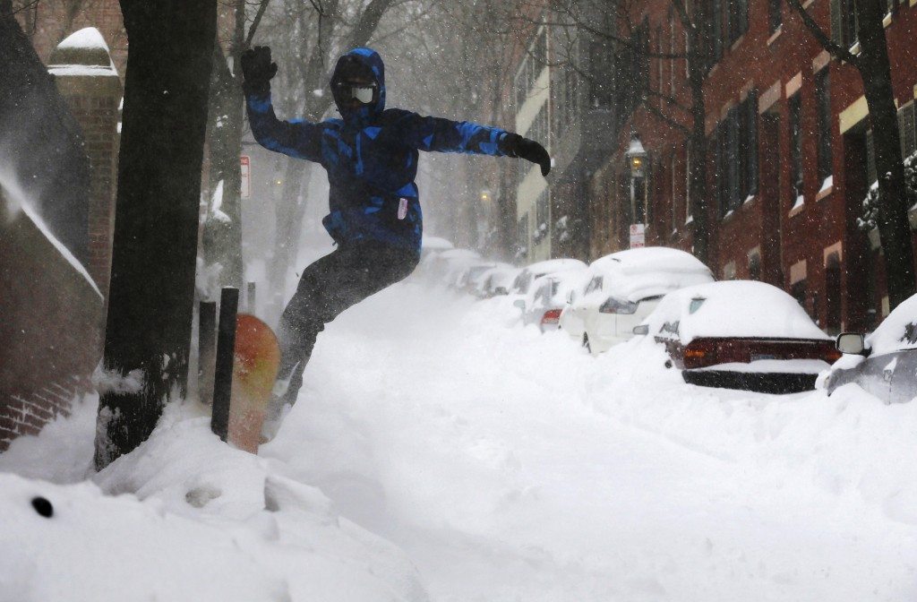 Will Adam, 14, snowboards down a street on Beacon Hill during a winter blizzard in Boston, Massachusetts. REUTERS/Brian Snyder