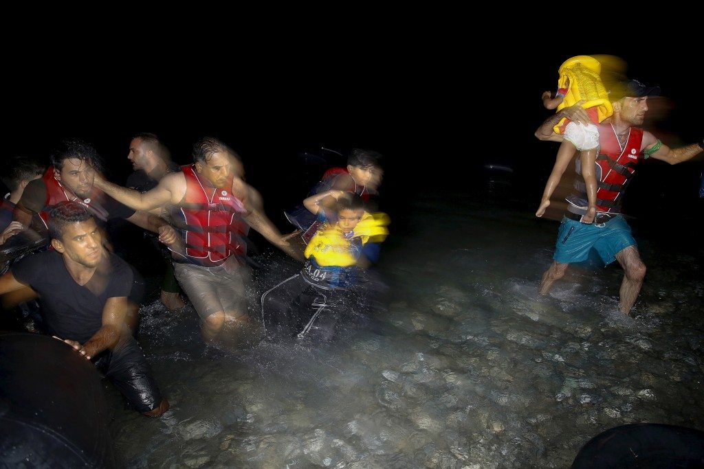 Syrian refugees carry their children as they jump off a dinghy overcrowded with Syrian refugees upon arriving on a beach on the Greek island of Kos, after crossing a part of the Aegean sea from Turkey, August 9, 2015. United Nations refugee agency (UNHCR) called on Greece to take control of the "total chaos" on Mediterranean islands, where thousands of migrants have landed. About 124,000 have arrived this year by sea, many via Turkey, according to Vincent Cochetel, UNHCR director for Europe. REUTERS/Yannis Behrakis - RTX1NMZH