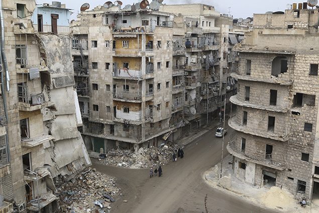 People walk past damaged buildings in Aleppo's al-Shaar district.
REUTERS/Mahmoud Hebbo 