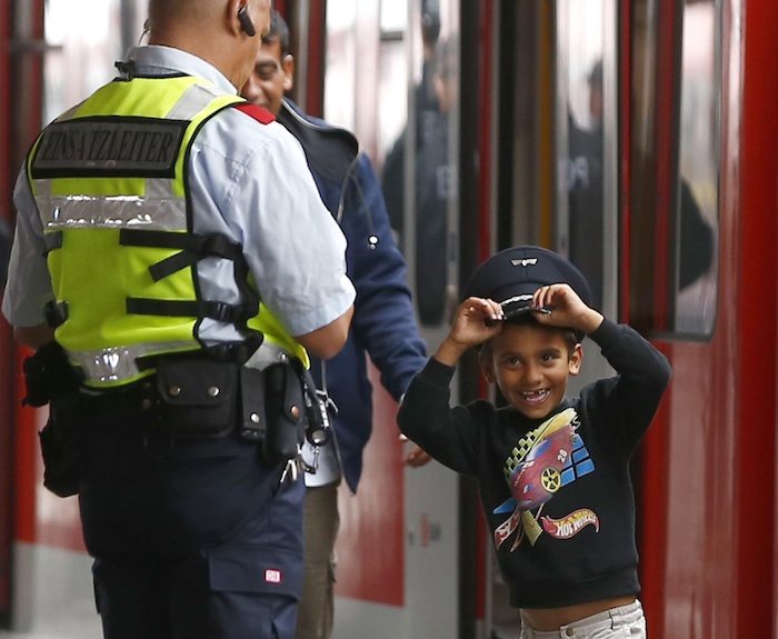 A young migrant boy tries on a Bahn security officer's cap after arriving with the first 'special' train from Salzberg, before boarding a regional S-Bahn train, at the main station in Munich, Germany September 5, 2015.