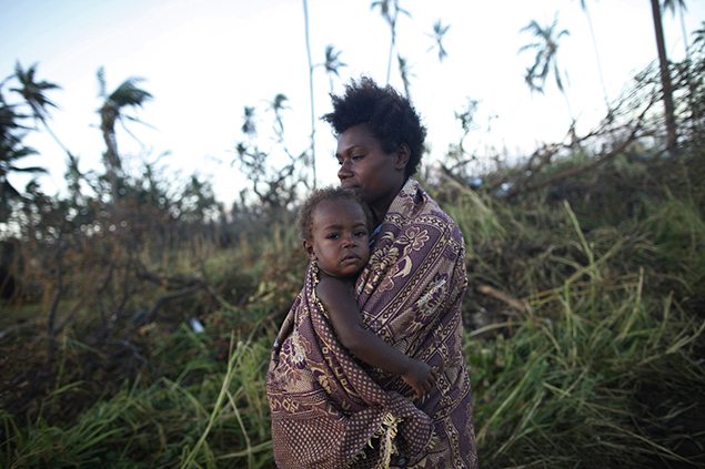 A woman carrying her baby walks past fallen trees in Tanna after the devastating cyclone in Vanuatu.
The powerful storm affected more than two-thirds of the South Pacific island nation wiping out crops and destroying fishing fleets.  REUTERS/Edgar Su 