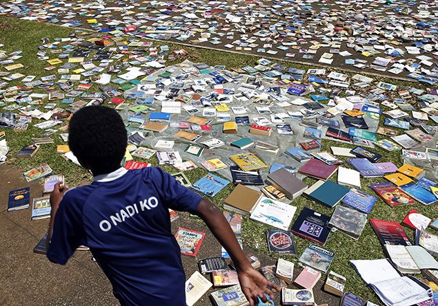 A boy runs past books laid to dry in the sun after the roof of the Central School library was blown away by Cyclone Pam in Port Vila, the capital city of the Pacific island nation of Vanuatu. REUTERS/Edgar Su